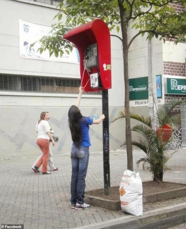 This picture, thought to be taken in Colombia, shows a woman struggling to reach a telephone which is placed at an unobtainable height