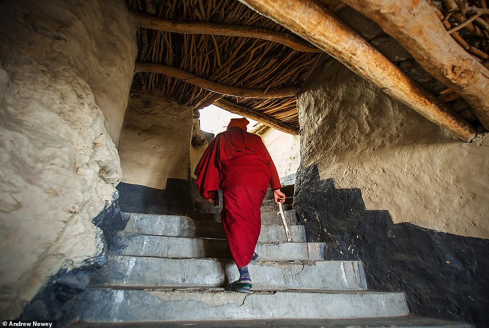 A monk climbs the many stairs to the rooftop for early morning prayers at the Phugtal Monastery
