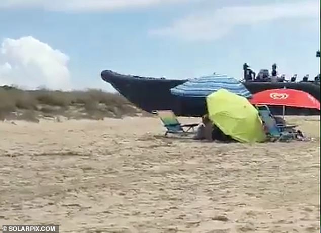 The men were filmed heading towards the sand at speed and narrowly missing parasols sunseekers had moved away from in a hurry as they rammed it into dunes