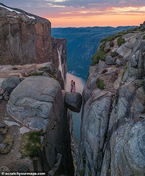 Danni and Fede stand on Kjeragbolten, a boulder jammed into a crevice 984m (3,228ft) above sea level on Kjerag mountain in the Lysefjord in Norway. The popular tourist destination can be reached without any hiking equipment